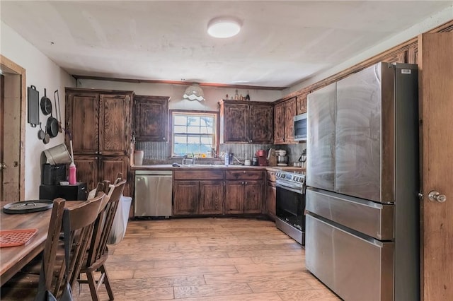 kitchen with light wood-style floors, appliances with stainless steel finishes, dark brown cabinetry, and a sink