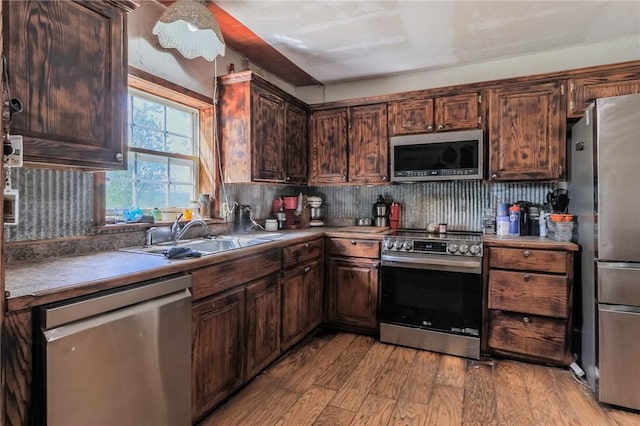 kitchen featuring dark brown cabinetry, appliances with stainless steel finishes, a sink, light wood-style floors, and decorative backsplash