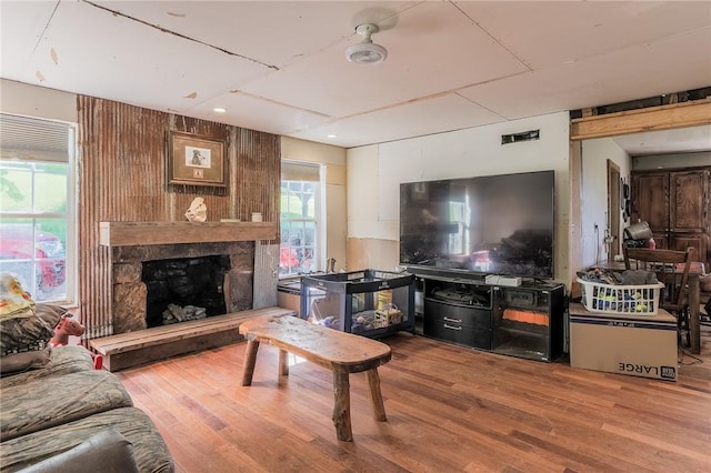 living area with visible vents, a stone fireplace, wood finished floors, and a wealth of natural light