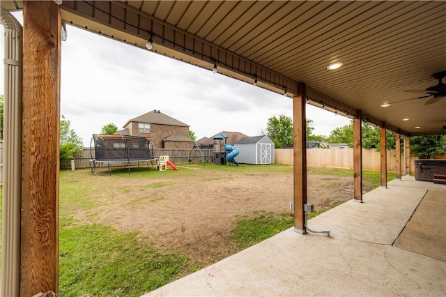 view of yard featuring a storage shed, a trampoline, a fenced backyard, and a patio area
