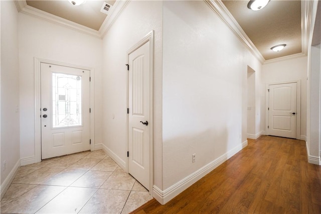 entrance foyer featuring baseboards, ornamental molding, light wood-style flooring, and visible vents