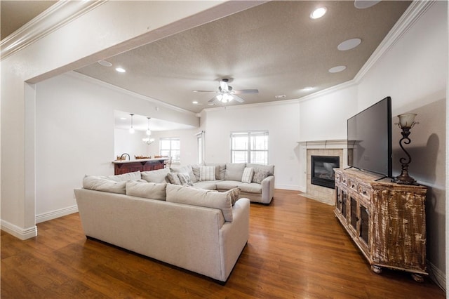 living area featuring dark wood-style flooring, a ceiling fan, baseboards, and ornamental molding