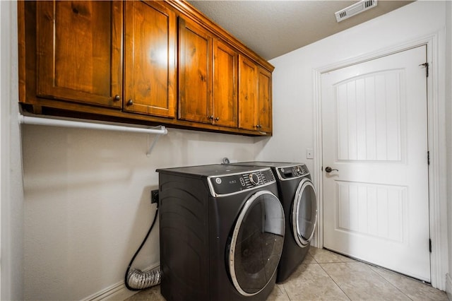 laundry room featuring cabinet space, independent washer and dryer, visible vents, and light tile patterned floors