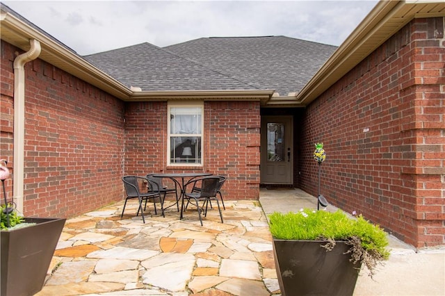 2915 N 15th Pl, Rogers, AR 72756 - doorway to property with brick siding, roof with shingles, a patio area, and outdoor dining space