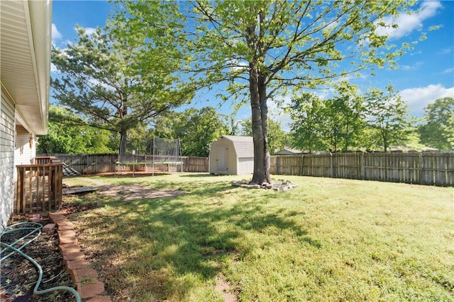 view of yard featuring a fenced backyard, an outdoor structure, a trampoline, and a storage unit