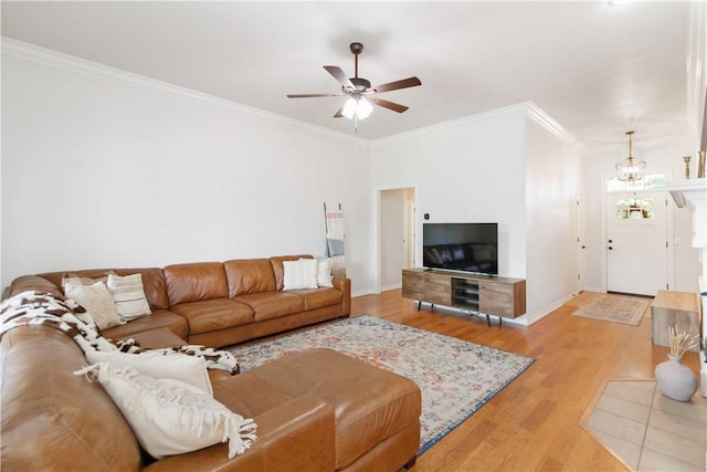 living room featuring baseboards, ornamental molding, light wood finished floors, and ceiling fan with notable chandelier