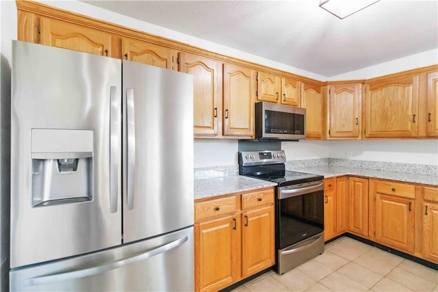 kitchen with light stone countertops, stainless steel appliances, and light tile patterned flooring