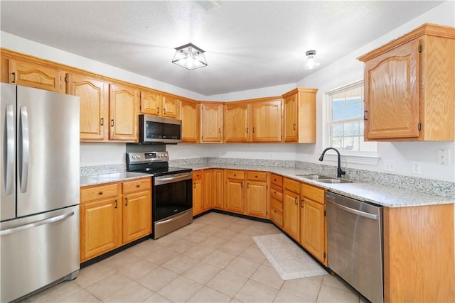 kitchen with a sink, light tile patterned floors, light stone countertops, and stainless steel appliances
