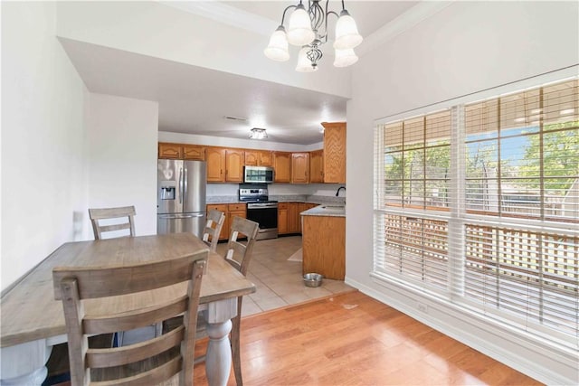 dining area with crown molding, baseboards, a chandelier, and light wood-style floors