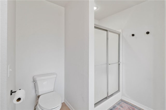 full bath with baseboards, a shower stall, and toilet