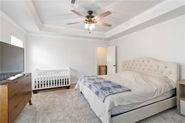 carpeted bedroom with crown molding, a ceiling fan, and a tray ceiling