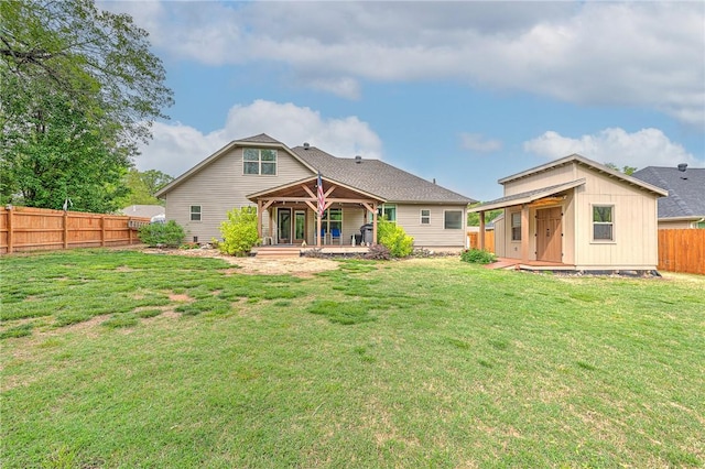 back of property with a fenced backyard, an outbuilding, and a yard