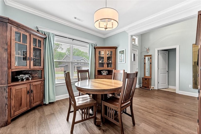 dining area featuring crown molding, baseboards, light wood finished floors, and visible vents