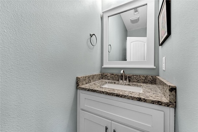 bathroom featuring vanity, a textured wall, and visible vents