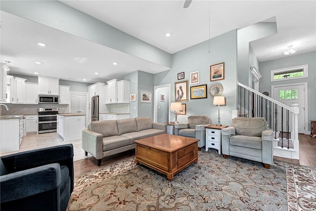 living area featuring light wood-style floors, recessed lighting, and stairway
