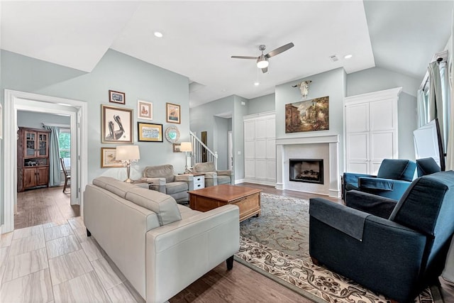 living area with a fireplace, a ceiling fan, recessed lighting, vaulted ceiling, and stairway