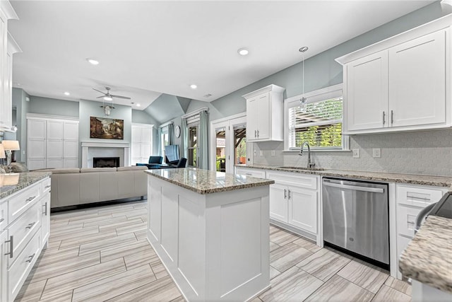 kitchen with backsplash, a ceiling fan, a fireplace, dishwasher, and a sink