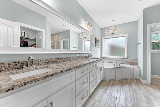 bathroom with a garden tub, a sink, a notable chandelier, and a spacious closet