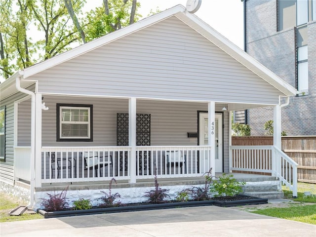 bungalow featuring a porch and fence