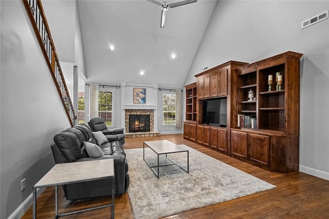 living room with visible vents, a fireplace, wood finished floors, high vaulted ceiling, and baseboards