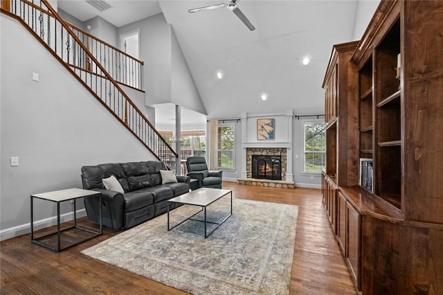 living room featuring a ceiling fan, a towering ceiling, a fireplace, wood finished floors, and recessed lighting