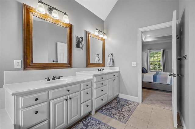 ensuite bathroom featuring tile patterned flooring, double vanity, baseboards, a sink, and vaulted ceiling