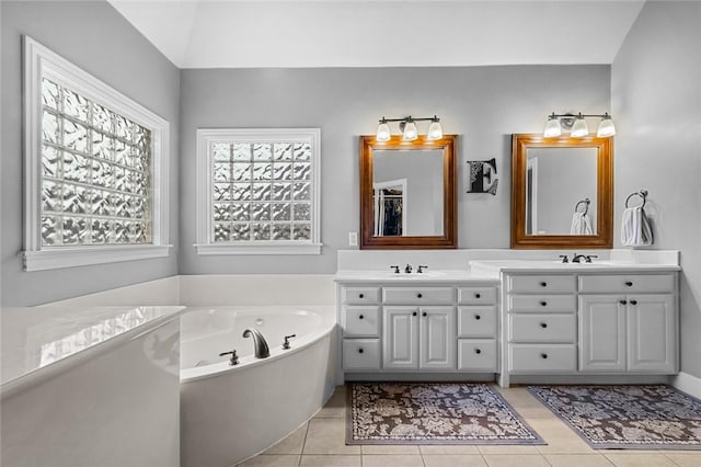 full bathroom featuring double vanity, tile patterned floors, a tub with jets, and a sink