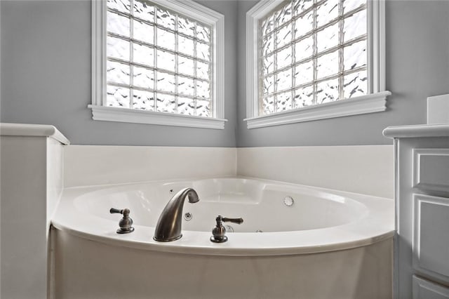 bathroom featuring a jetted tub and a wealth of natural light