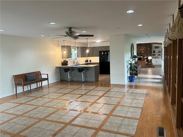 kitchen featuring a peninsula, a ceiling fan, black fridge with ice dispenser, visible vents, and light countertops