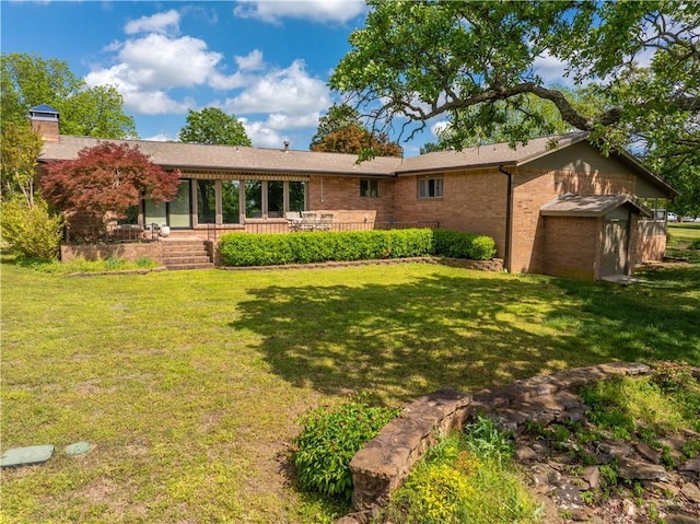 view of front of house featuring brick siding, a chimney, and a front yard