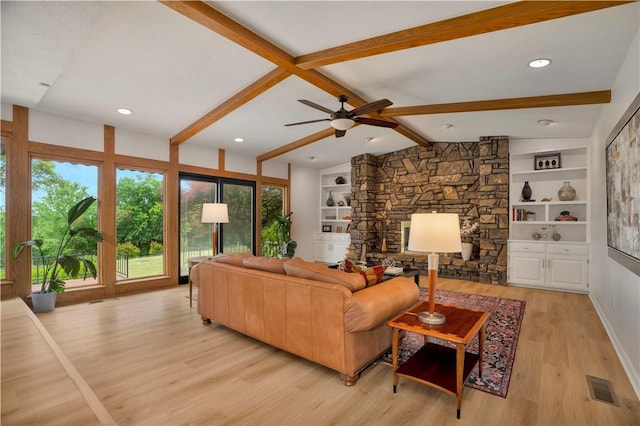 living room with lofted ceiling with beams, visible vents, ceiling fan, a stone fireplace, and light wood-style floors