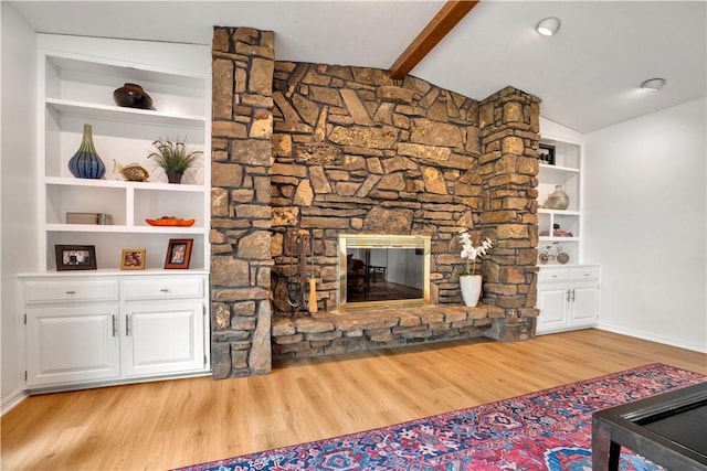 unfurnished living room featuring baseboards, light wood-style flooring, lofted ceiling with beams, and a stone fireplace