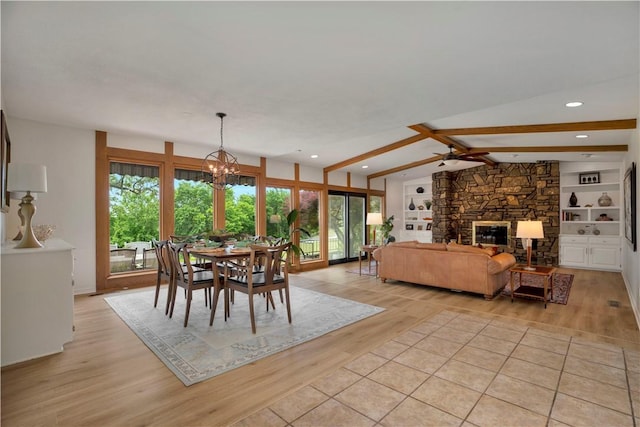 dining area with lofted ceiling with beams, recessed lighting, an inviting chandelier, a stone fireplace, and light wood-style floors