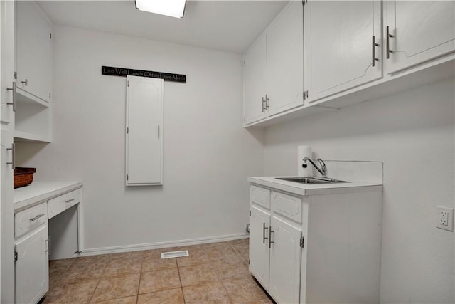 clothes washing area featuring a sink, light tile patterned flooring, baseboards, and visible vents