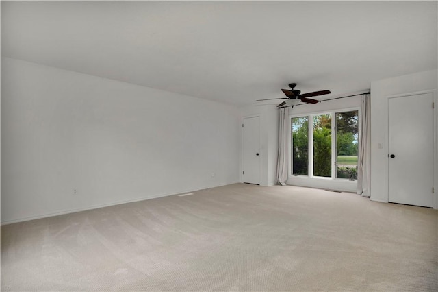 spare room with light carpet, baseboards, and a ceiling fan