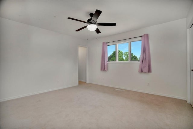 empty room with baseboards, light carpet, and ceiling fan