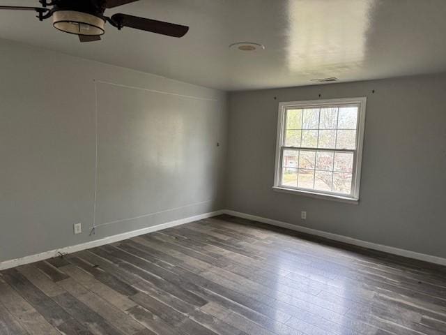 empty room with baseboards, dark wood finished floors, and ceiling fan