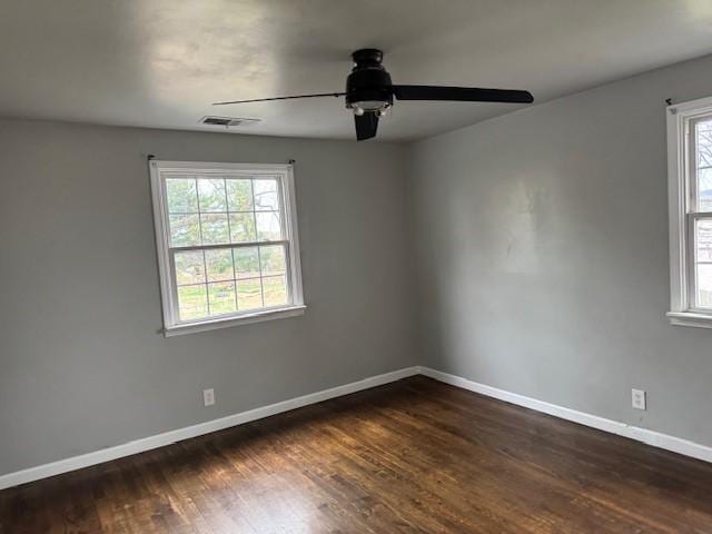 empty room with ceiling fan, visible vents, dark wood-style floors, and baseboards