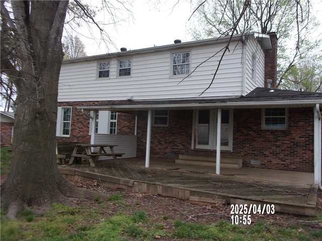rear view of property with brick siding, a deck, and entry steps