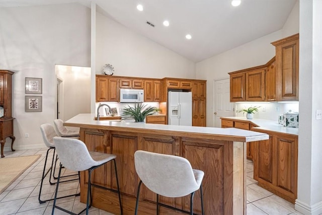 2 Breton Ln, Bella Vista, AR 72715 - kitchen with white appliances, high vaulted ceiling, light tile patterned floors, light countertops, and brown cabinetry