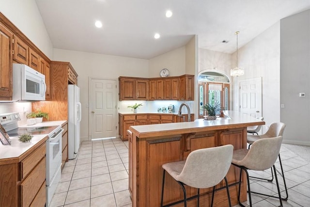 2 Breton Ln, Bella Vista, AR 72715 - kitchen with white appliances, a breakfast bar area, brown cabinetry, light countertops, and recessed lighting
