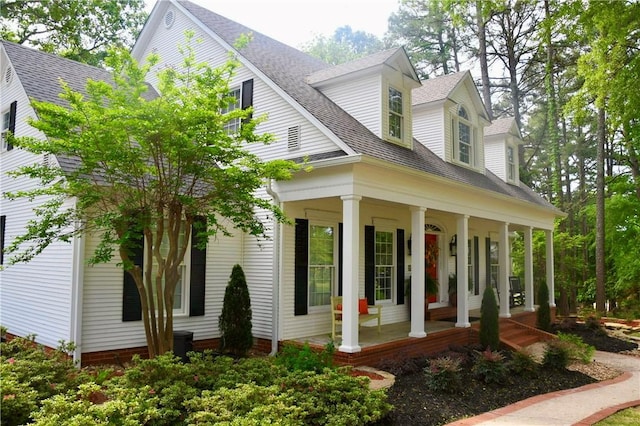 view of side of property featuring a shingled roof and covered porch
