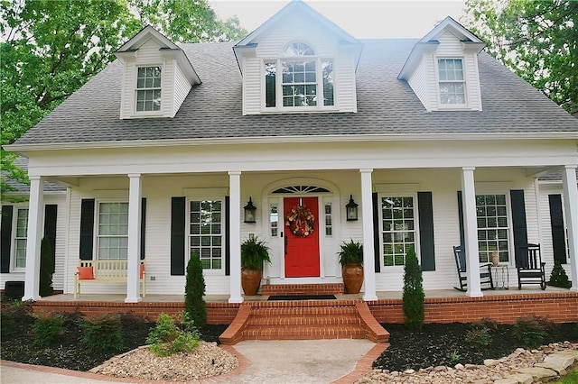 cape cod home with a porch and a shingled roof