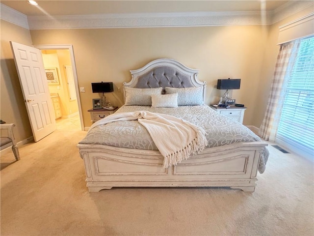 bedroom with light colored carpet, ornamental molding, baseboards, and connected bathroom