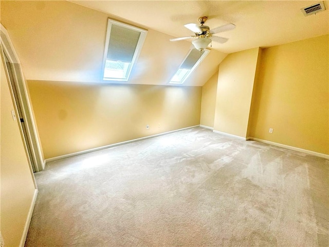 bonus room with carpet floors, a ceiling fan, lofted ceiling with skylight, and visible vents