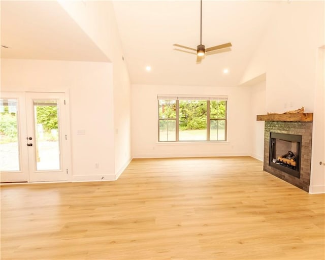 unfurnished living room with a tiled fireplace, baseboards, and a wealth of natural light