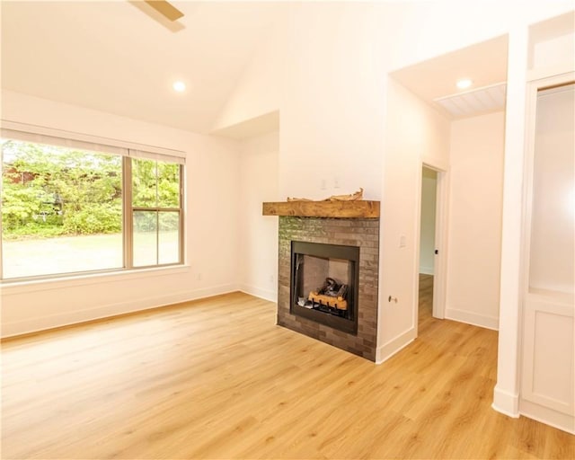 unfurnished living room with lofted ceiling, a fireplace, light wood-style floors, baseboards, and recessed lighting