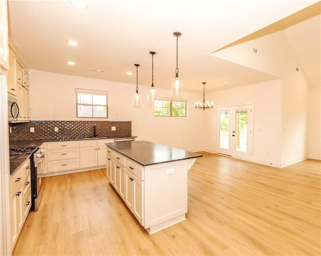 kitchen featuring a sink, gas stove, light wood-style flooring, a center island, and tasteful backsplash