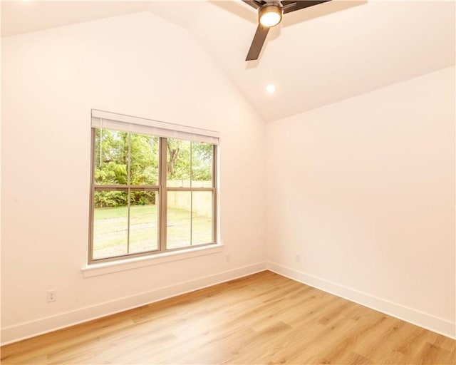 spare room featuring baseboards, a ceiling fan, lofted ceiling, and light wood-type flooring