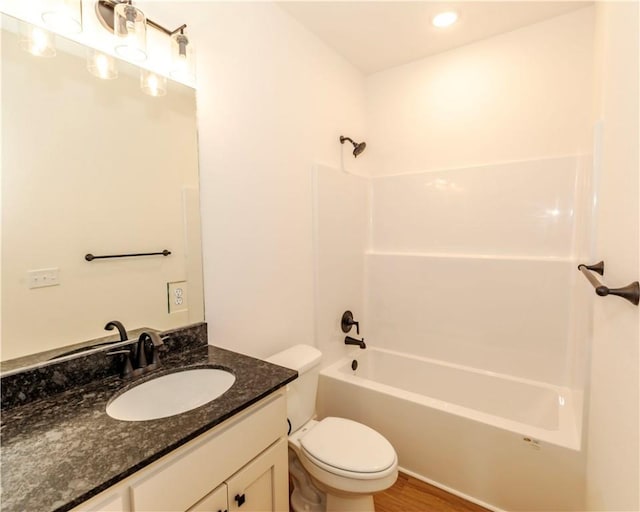bathroom featuring wood finished floors, vanity, toilet,  shower combination, and recessed lighting